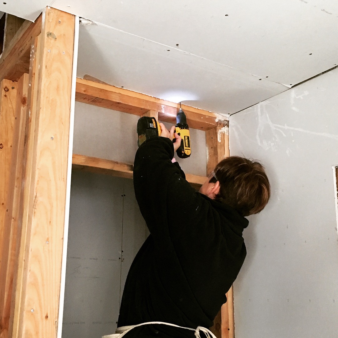 CBA Interim Co-executive Director Carol DeJohn hangs sheetrock inside the home.