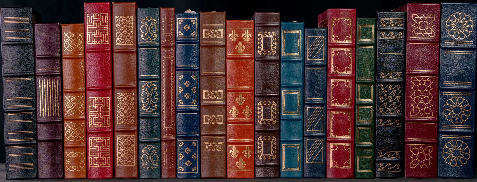 A-stack-of-beautiful-leather-bound-books-with-golden-decoration-against-a-black-background
